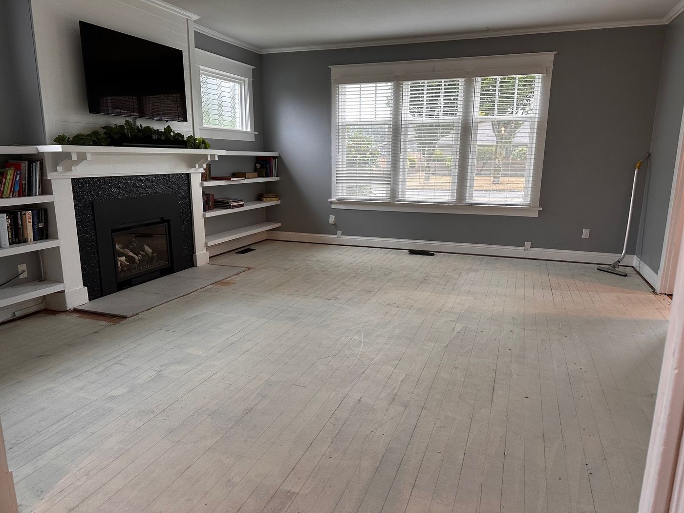 The same living room before, with worn bare subfloor